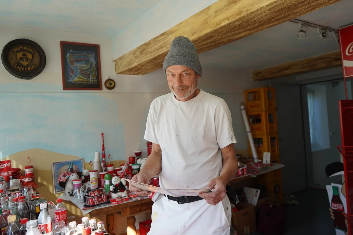 Man sieht Daniel Jaussi und seine Coca-Cola Sammlung.